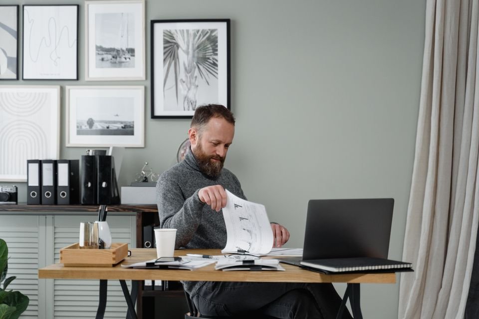 Professional reviewing paperwork beside a laptop at a desk