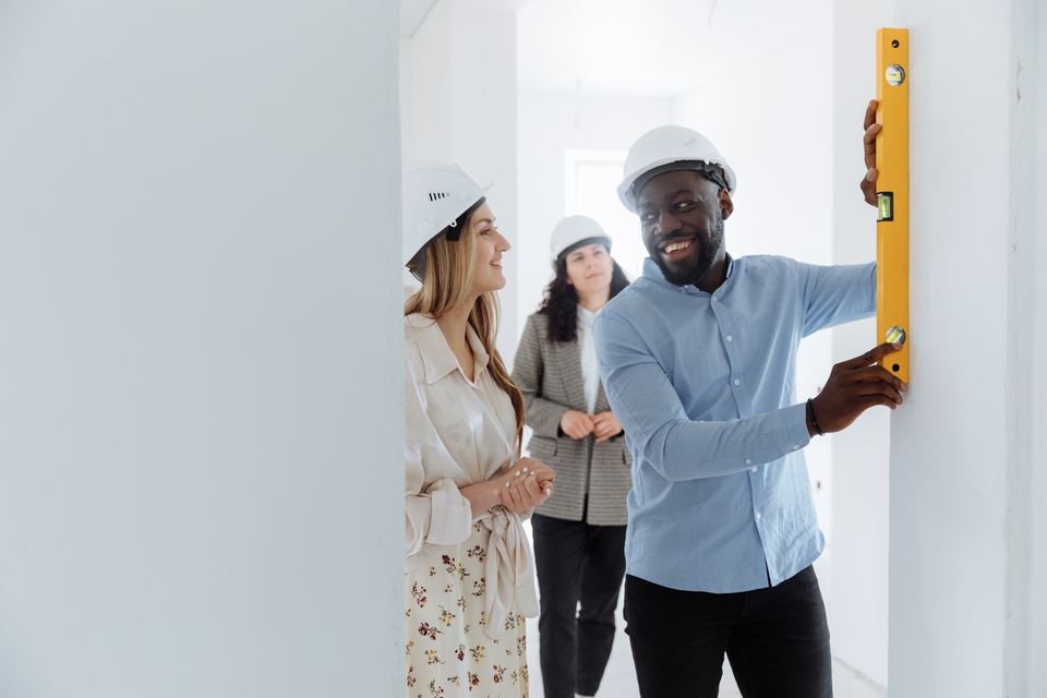 Smiling renovation professionals discussing an interior wall inspection